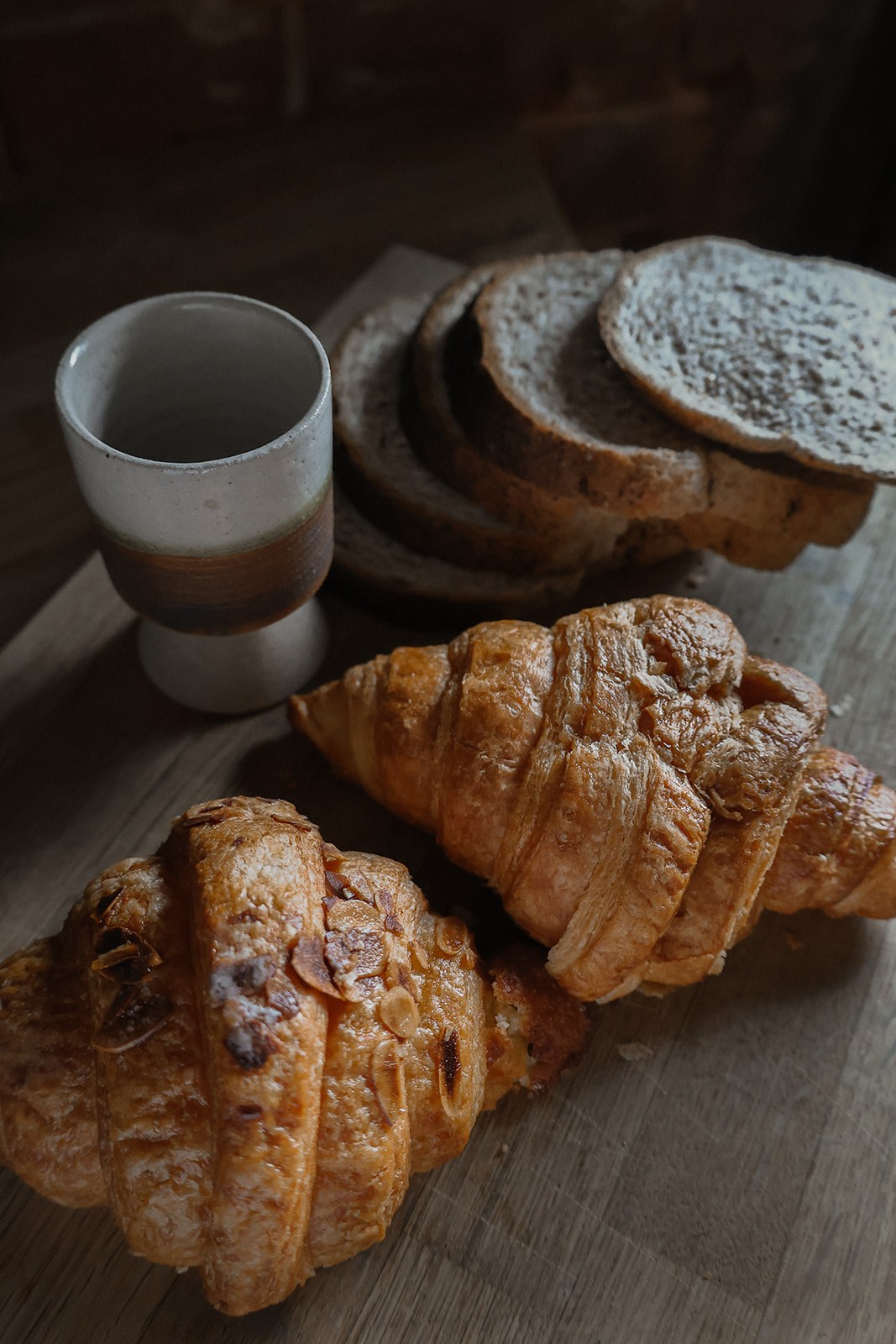 Croissants, toast and a cup of coffee on a wooden board at The Oast