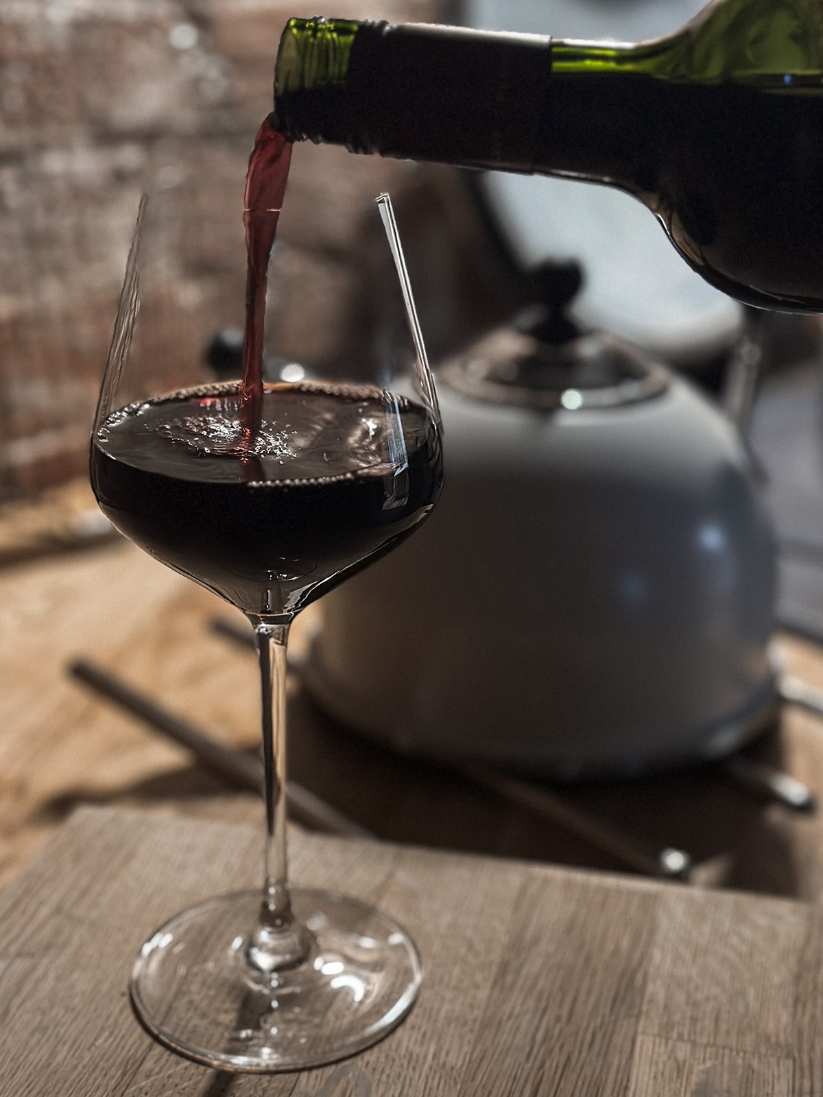 Red wine being poured into a glass beside the AGA at The Oast