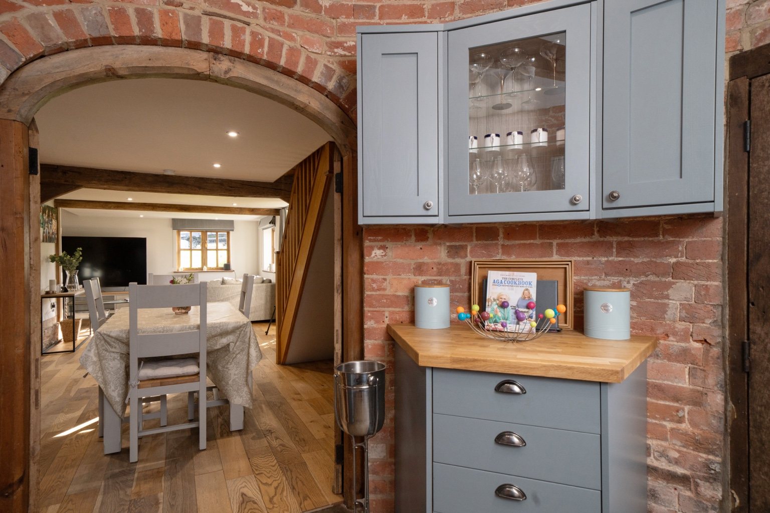 Looking through the brick and timber kitchen arch into the dining and sitting area at The Oast