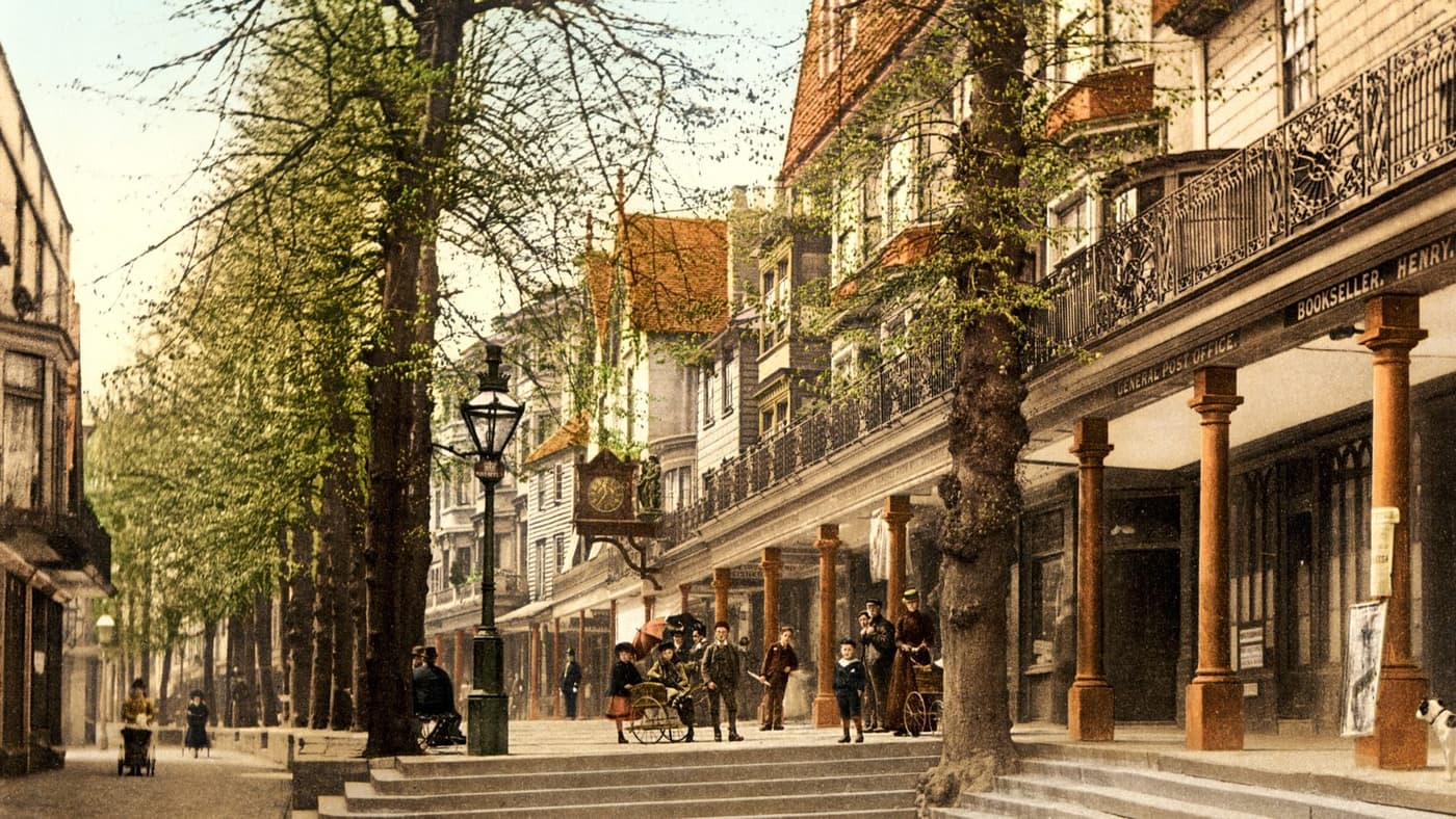 A colour photochrom of the Pantiles in Tunbridge Wells around 1895, showing the tree-lined promenade, colonnades, shopfronts and visitors in period dress