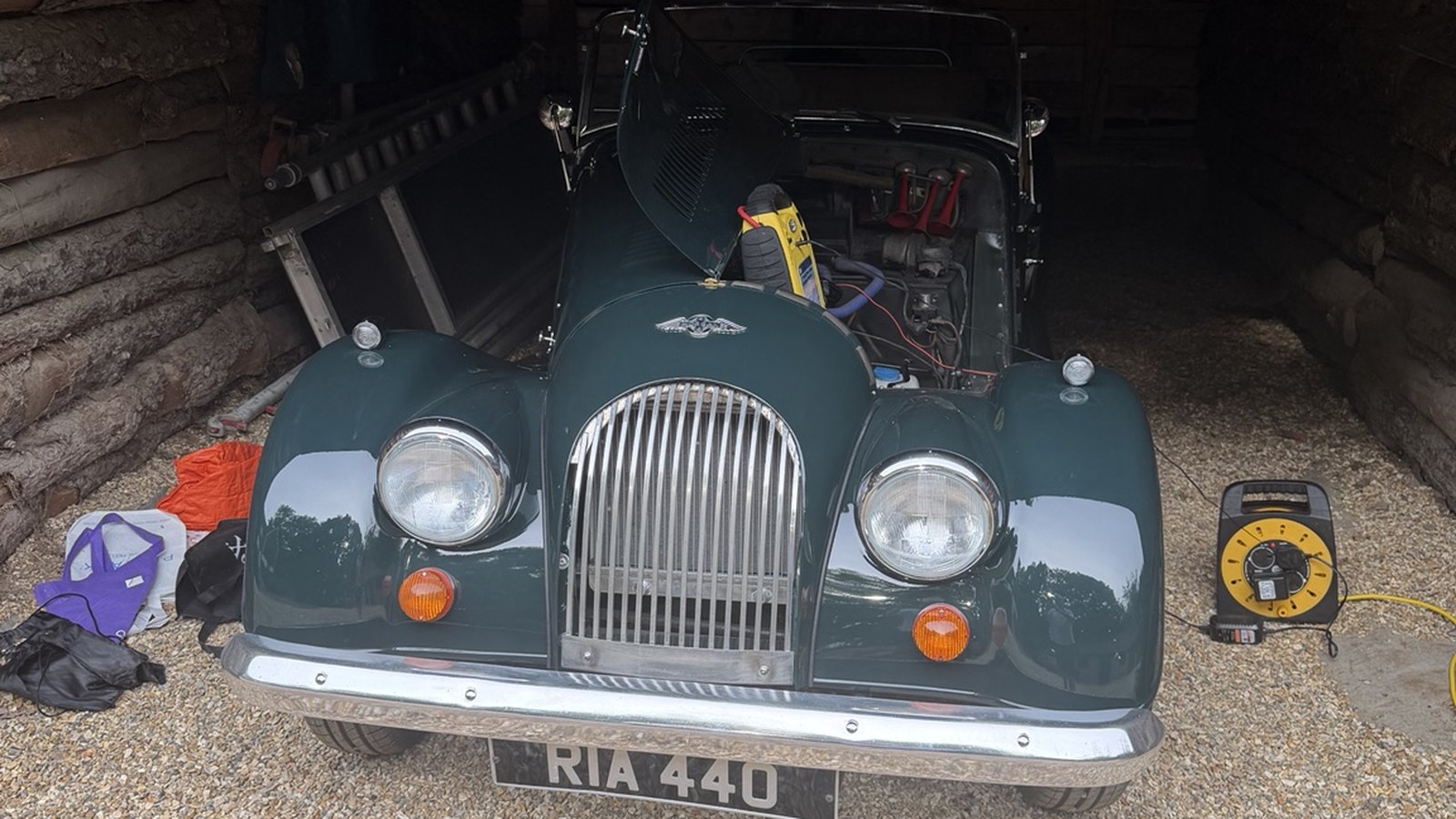 British Racing Green 1980 Morgan 4/4 in the barn at Martins Farm with its bonnet raised and a battery charger attached.