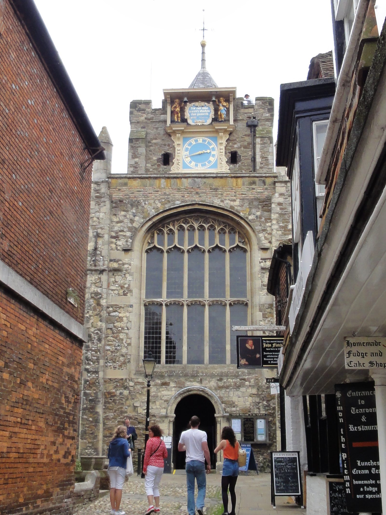 Lion Street in Rye looking up the cobbles to the clock and west front of St Mary's church, with brick and tile-hung shopfronts either side