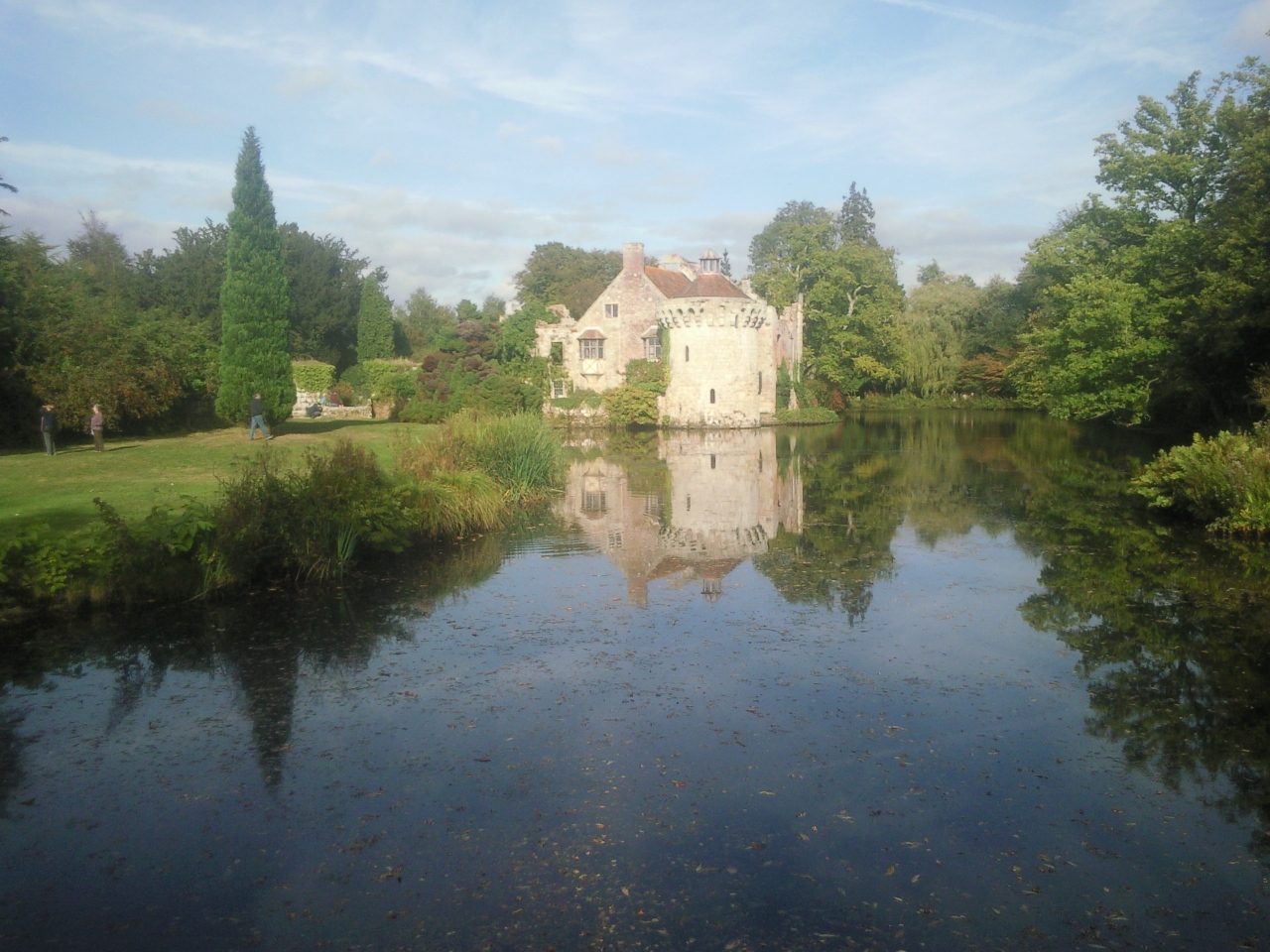 Scotney Castle in early autumn seen across the misty moat, the ruined tower pale among trees just beginning to turn